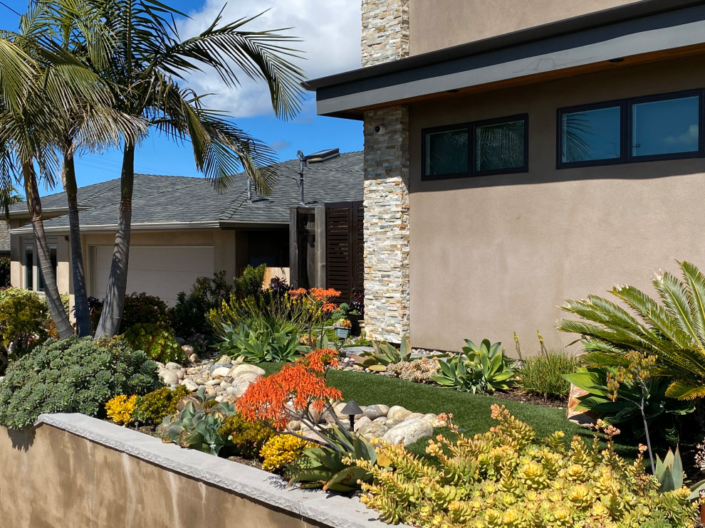 サンディエゴにあるお手頃価格の小さな、夏のコンテンポラリースタイルのおしゃれな前庭 (ゼリスケープ、擁壁、日向、川石舗装、金属フェンス) の写真