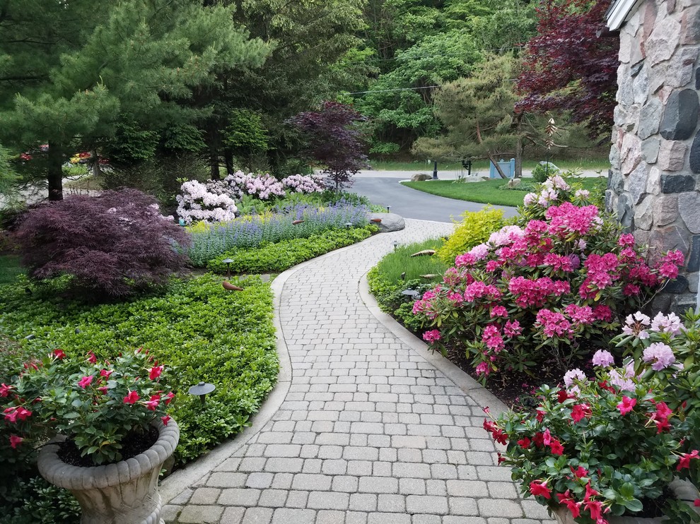 Design ideas for a medium sized romantic front driveway partial sun garden for summer in Grand Rapids with a garden path and brick paving.