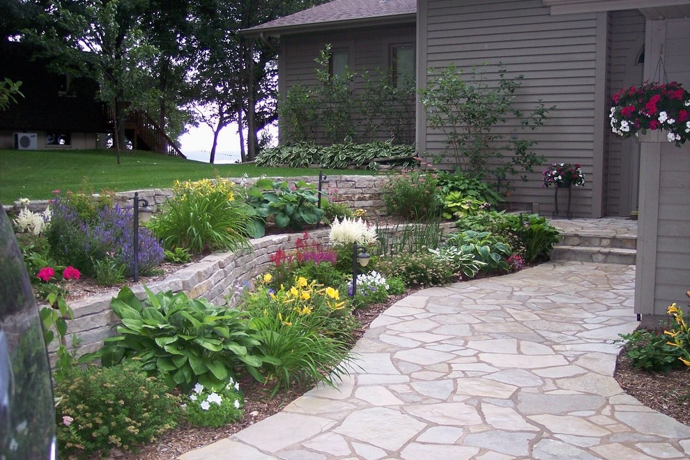 Idee per un giardino chic di medie dimensioni e davanti casa con un muro di contenimento e pavimentazioni in pietra naturale
