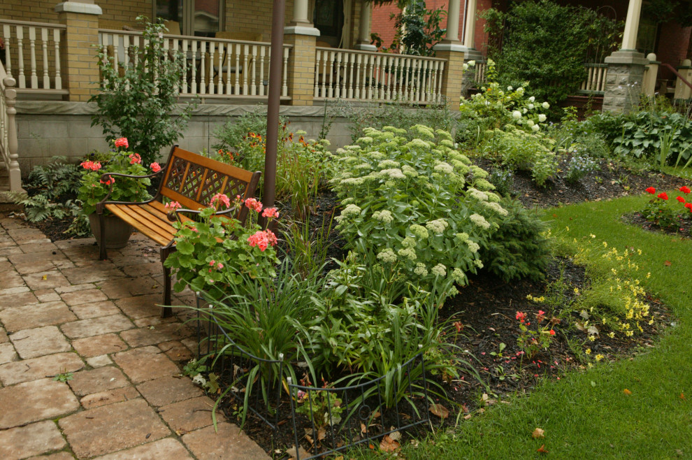 Imagen de jardín clásico renovado de tamaño medio en patio delantero con jardín francés, parterre de flores, exposición reducida al sol y adoquines de ladrillo