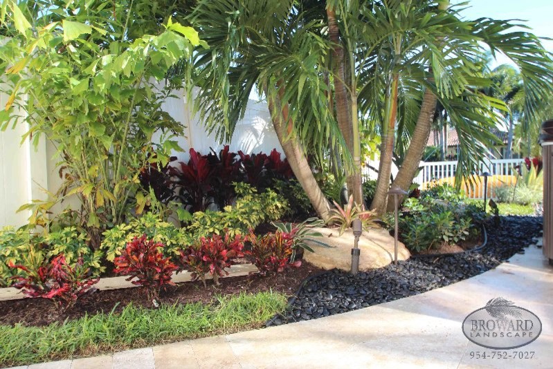 This is an example of a mid-sized tropical partial sun backyard gravel landscaping in Miami.