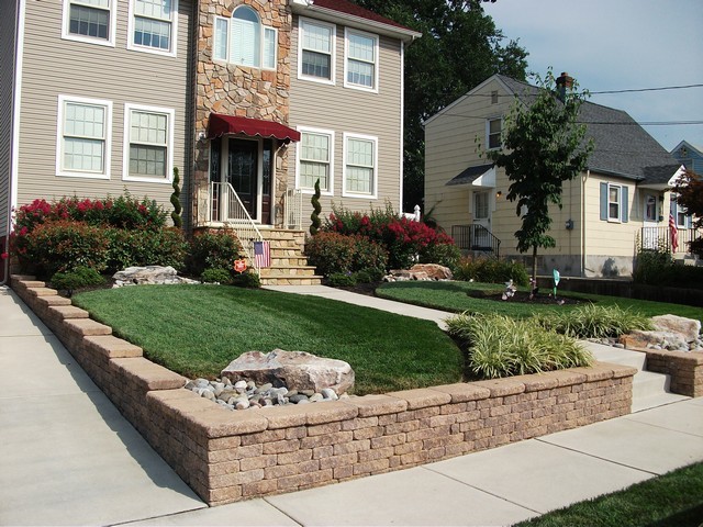 Пример оригинального дизайна: солнечный, летний участок и сад среднего размера на переднем дворе с подпорной стенкой, хорошей освещенностью и мощением тротуарной плиткой