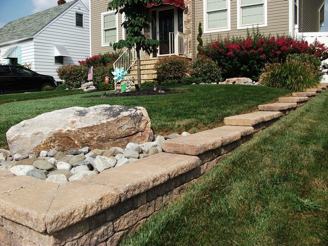 This is an example of a medium sized front full sun garden for summer in Philadelphia with a retaining wall and concrete paving.