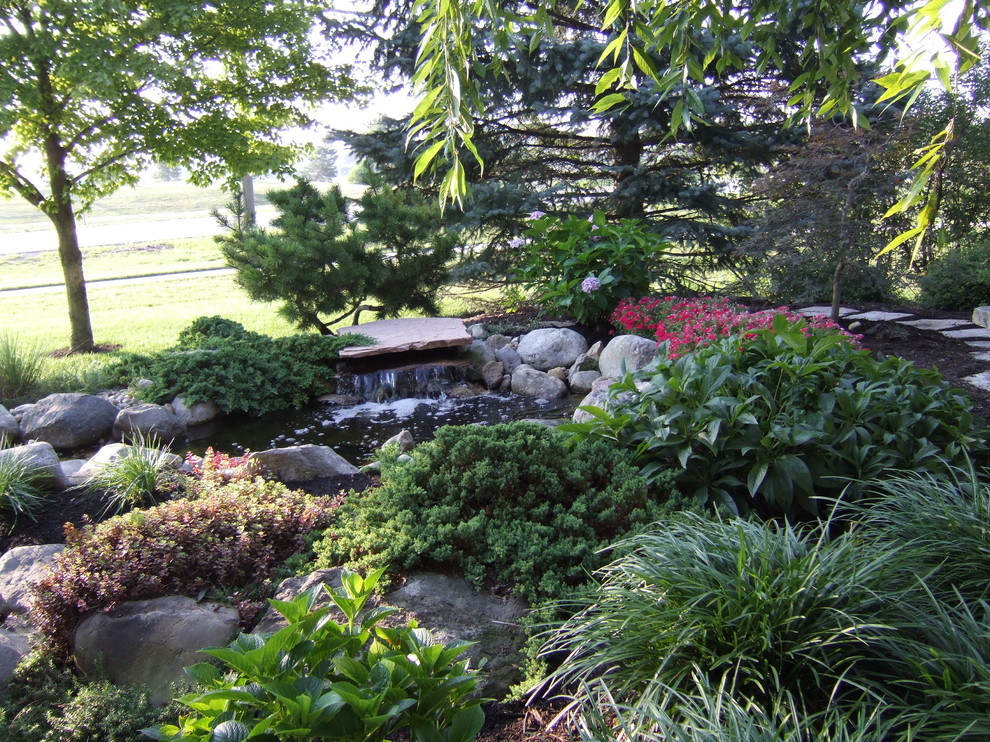 Photo of a medium sized bohemian front partial sun garden for summer in Columbus with a water feature and concrete paving.
