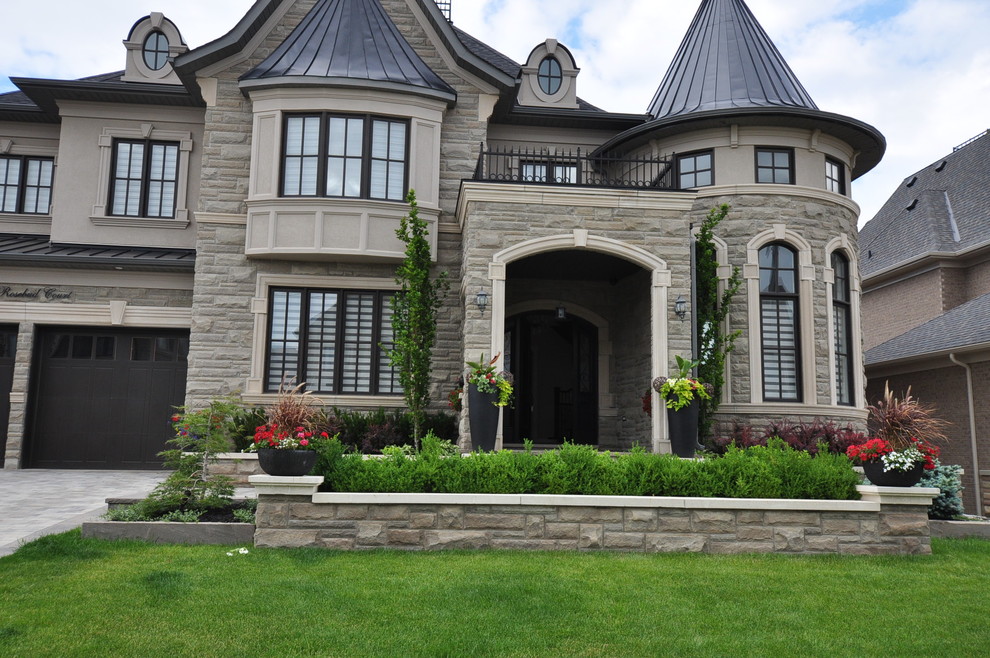 Design ideas for a mid-sized traditional front yard stone landscaping in Toronto.