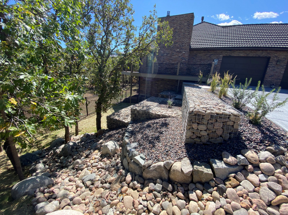 Inspiration for a medium sized traditional back driveway partial sun garden in Denver with a retaining wall and decorative stones.