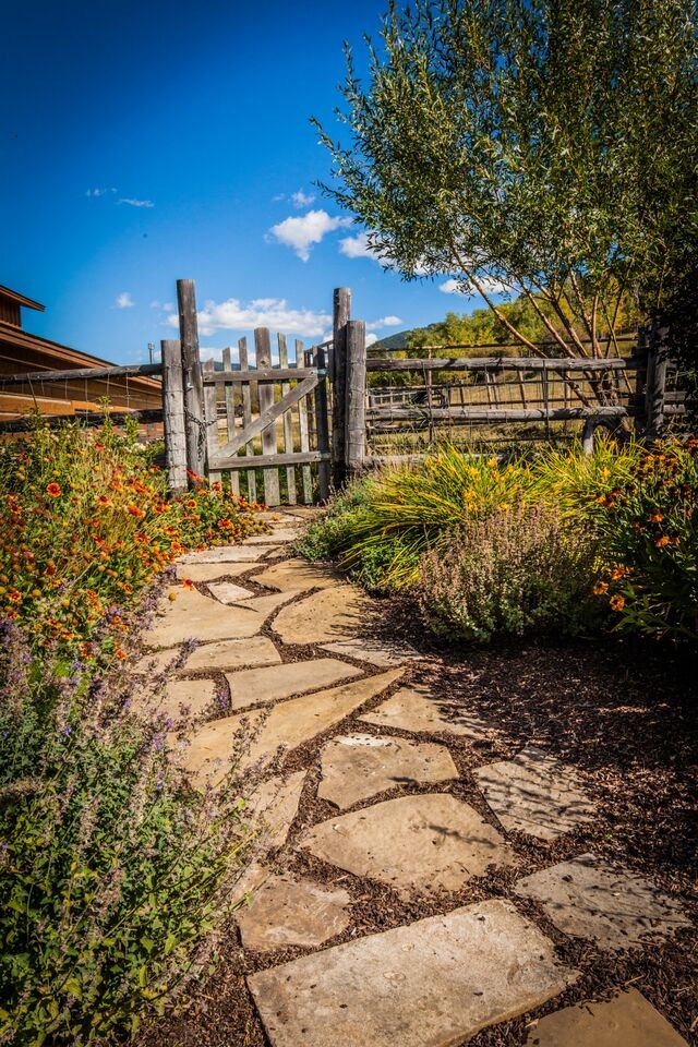 Photo of a mid-sized rustic full sun backyard stone landscaping in Other for spring.