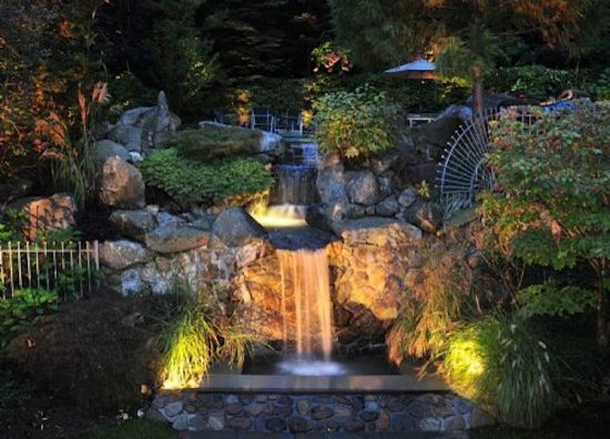 Foto de jardín tradicional grande en patio trasero con fuente y adoquines de piedra natural