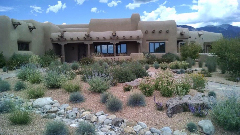 This is an example of a large southwestern drought-tolerant and partial sun front yard stone landscaping in Albuquerque.