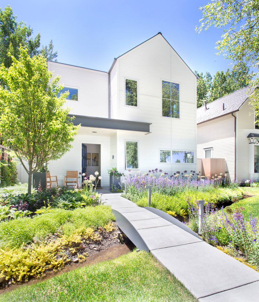 Exempel på en minimalistisk trädgård framför huset, med en trädgårdsgång och marksten i betong
