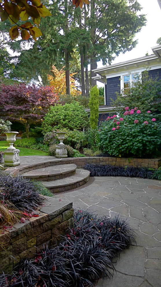 Modelo de jardín clásico pequeño en patio trasero con adoquines de piedra natural, muro de contención y exposición reducida al sol