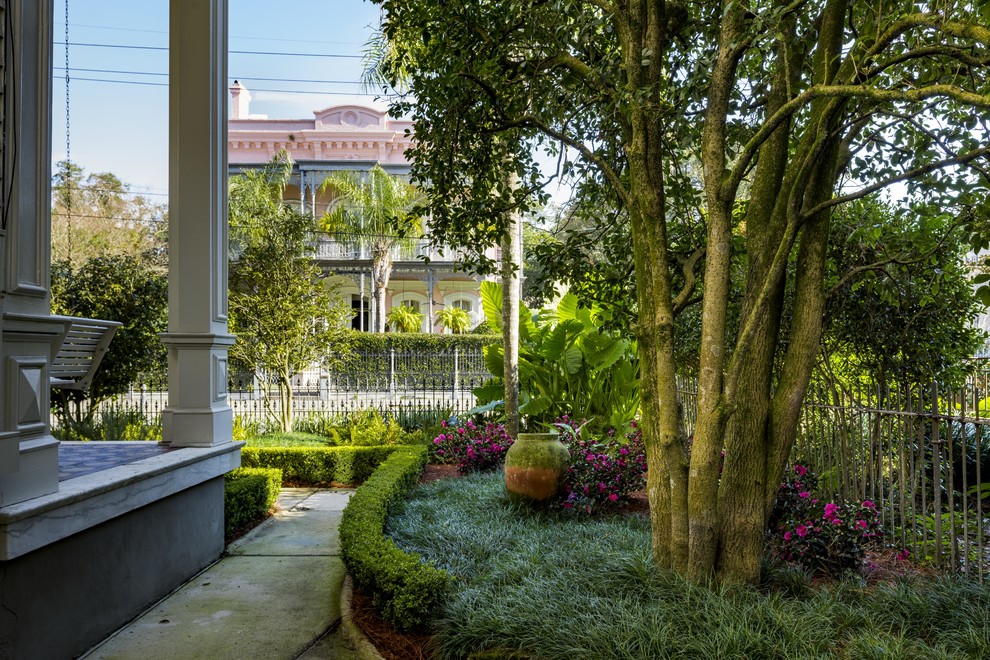Small classic front formal partial sun garden in New Orleans with a garden path.