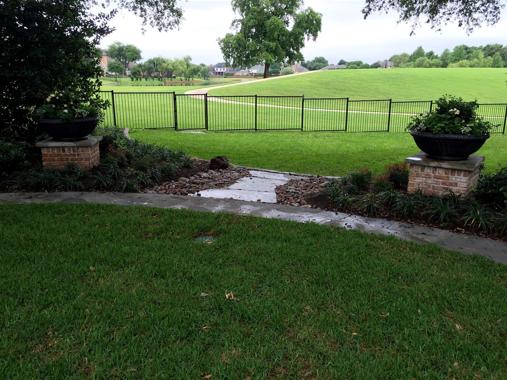 Photo of a large traditional back fully shaded garden in Dallas with natural stone paving.