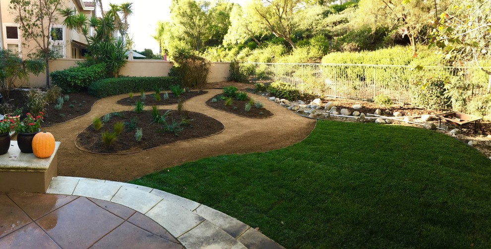 Cette photo montre un grand jardin arrière chic avec une exposition ensoleillée et des pavés en pierre naturelle.