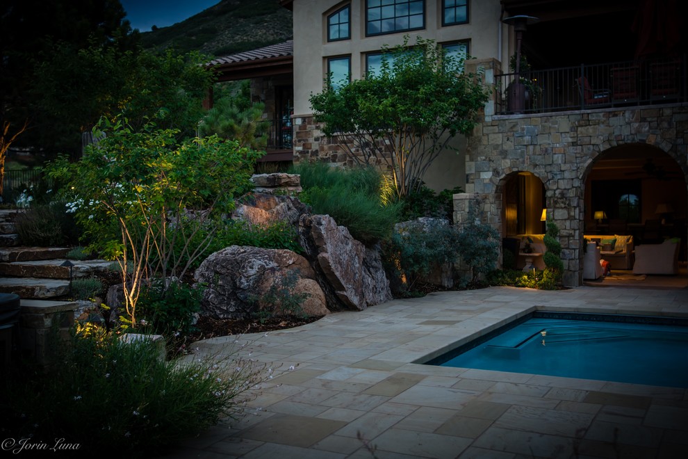 This is an example of an expansive rustic back xeriscape full sun garden in Denver with natural stone paving.
