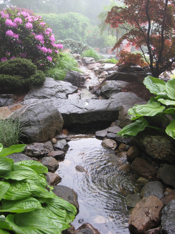 Cette image montre un jardin arrière traditionnel avec une exposition ombragée, des pavés en pierre naturelle et un point d'eau.