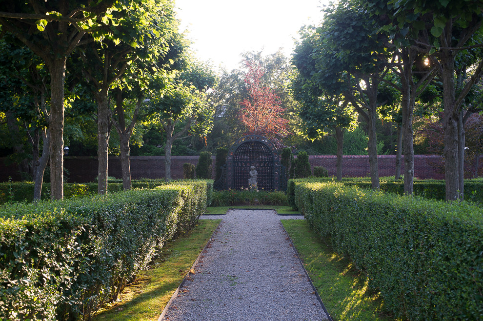 Imagen de jardín clásico en patio trasero con gravilla y jardín francés