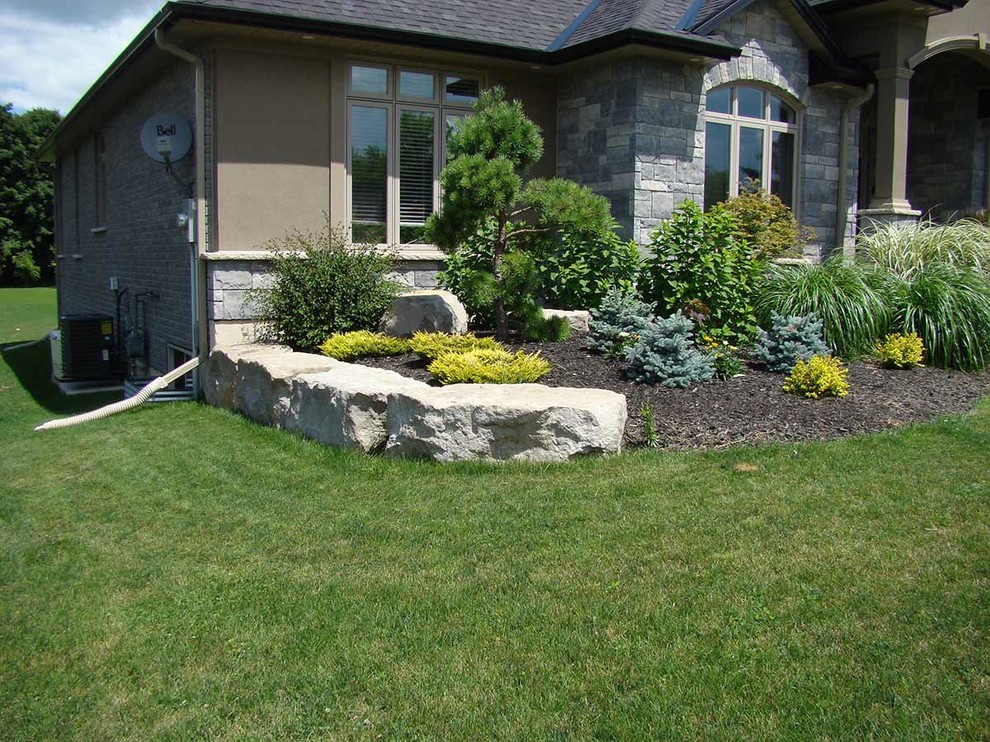 Photo of a large classic front full sun garden in Toronto with a retaining wall.