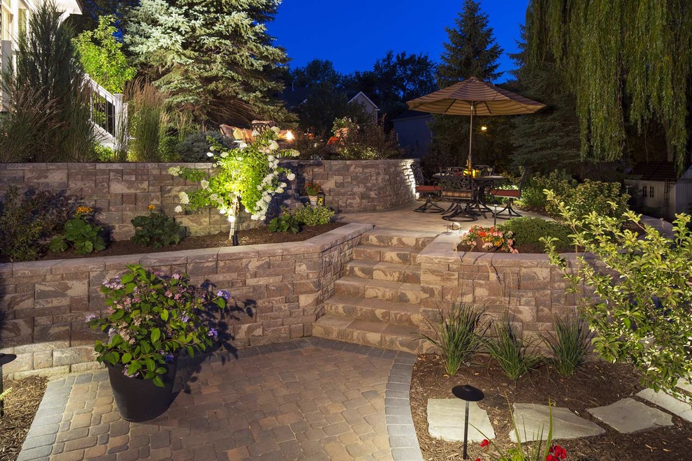 Diseño de jardín clásico de tamaño medio en patio trasero con jardín francés, muro de contención y adoquines de hormigón