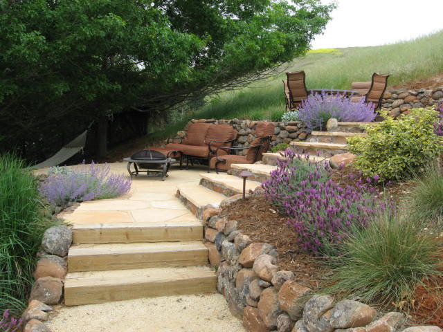 Ejemplo de jardín moderno de tamaño medio en patio trasero con brasero, exposición parcial al sol y adoquines de piedra natural