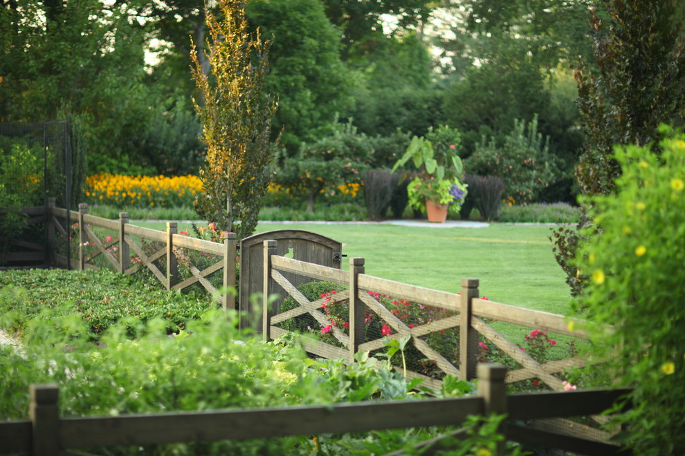 Exempel på en stor klassisk trädgård i full sol längs med huset på sommaren, med en köksträdgård och grus