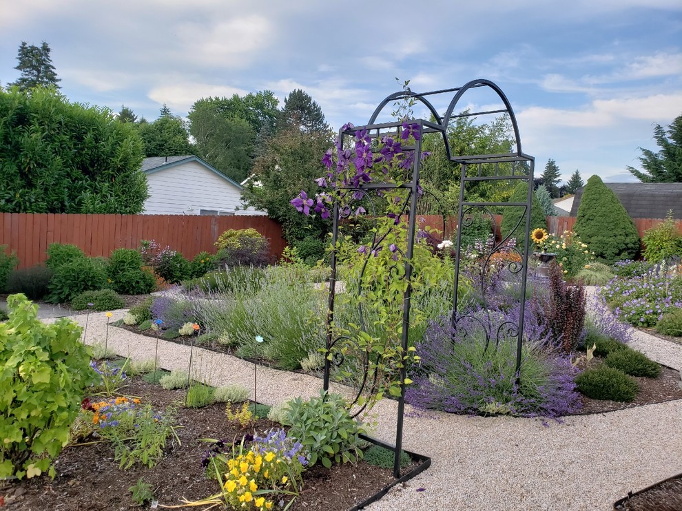 This is an example of a large traditional full sun backyard gravel landscaping in Portland for summer.