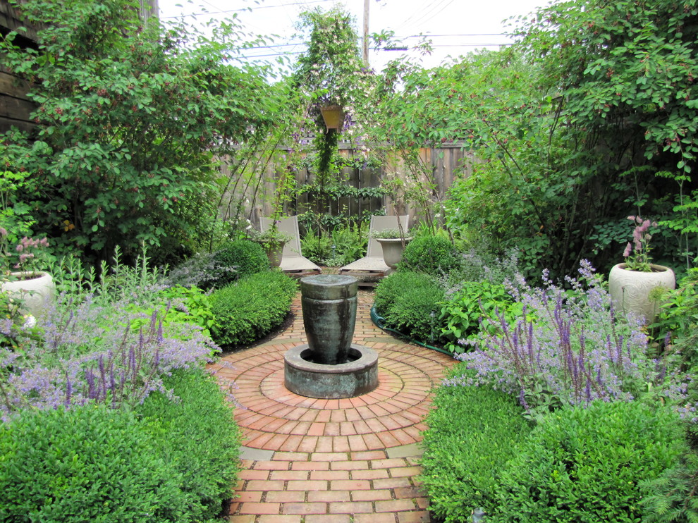 Cette image montre un jardin à la française arrière traditionnel de taille moyenne avec un point d'eau et des pavés en brique.