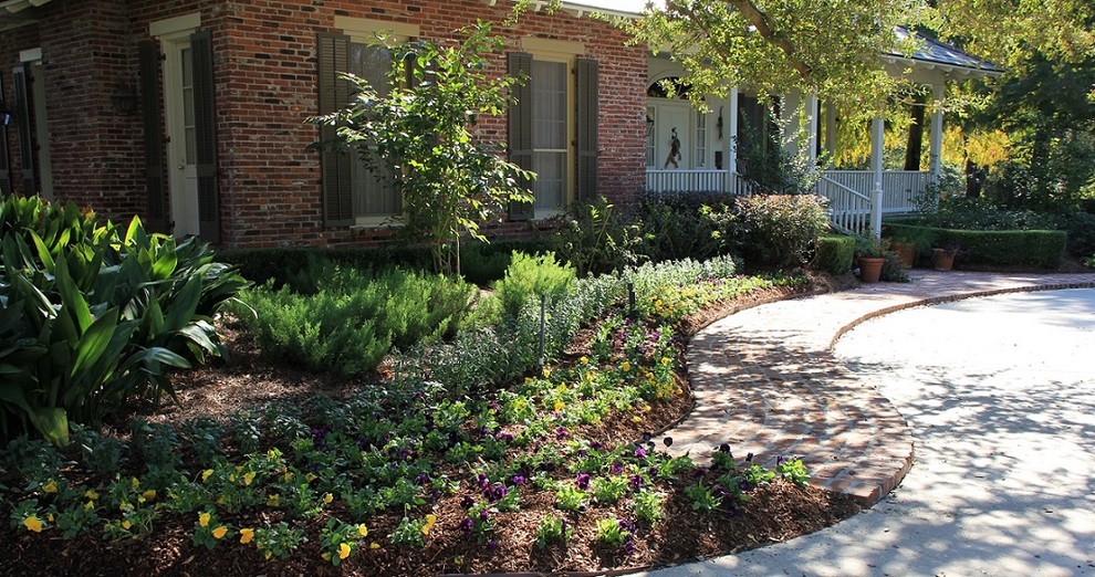 This is an example of a mid-sized traditional full sun front yard brick landscaping in New Orleans.