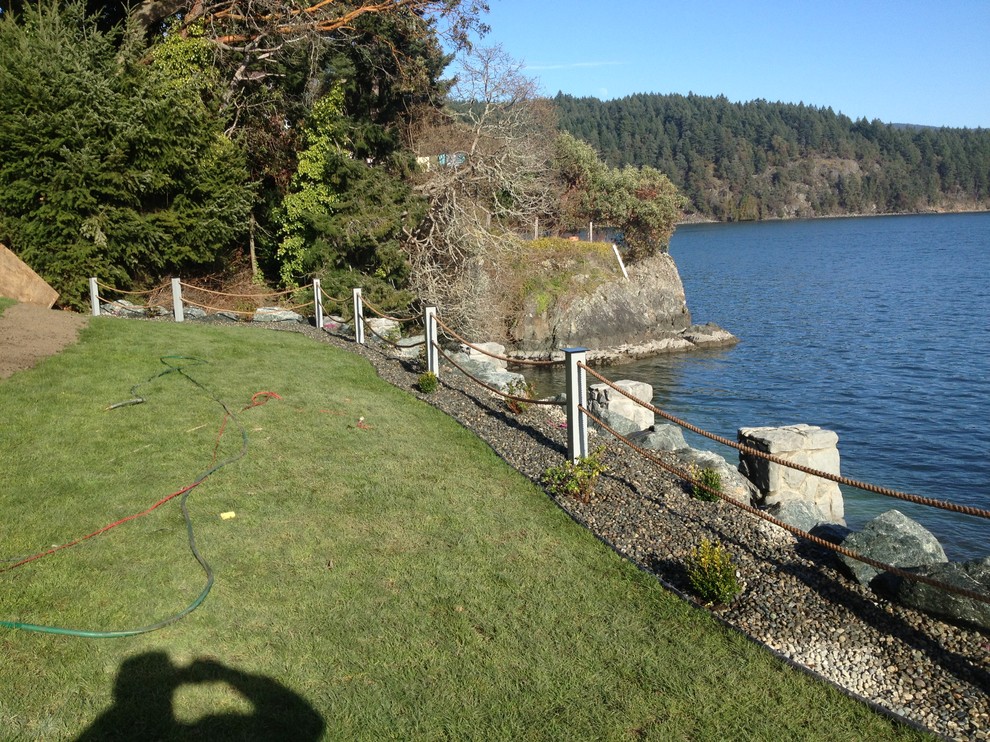 Photo of a mid-sized coastal partial sun backyard retaining wall landscape in Vancouver.