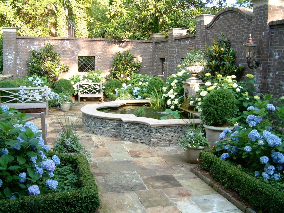 Idée de décoration pour un jardin à la française arrière tradition avec des pavés en pierre naturelle.