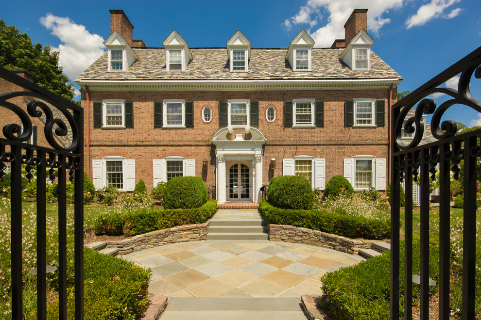 Photo of a large classic front formal full sun garden in New York with a garden path and natural stone paving.