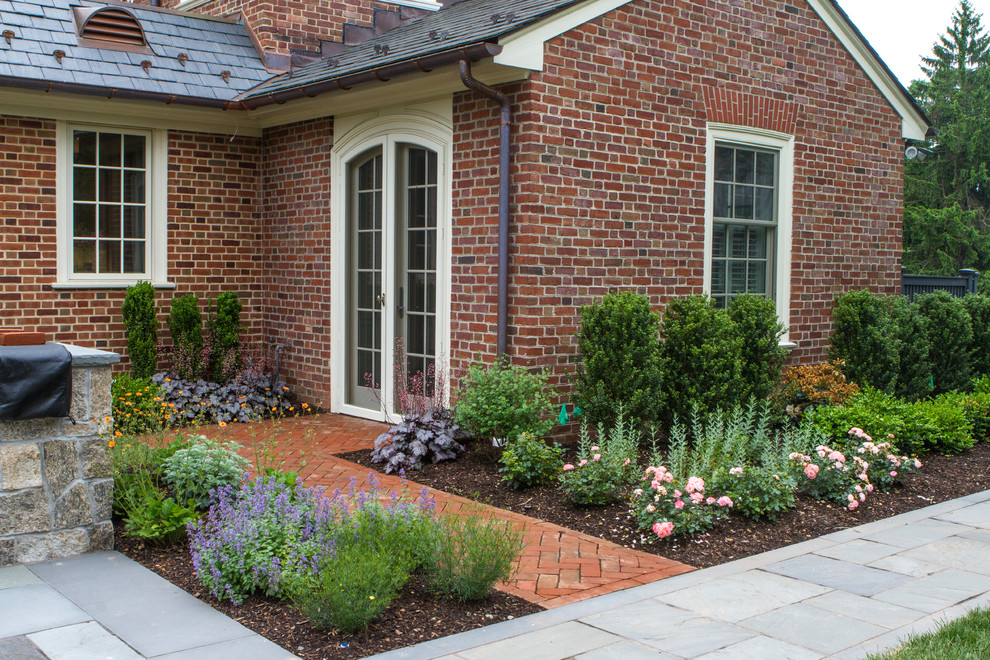 Foto di un grande giardino formale classico esposto in pieno sole davanti casa con pavimentazioni in pietra naturale