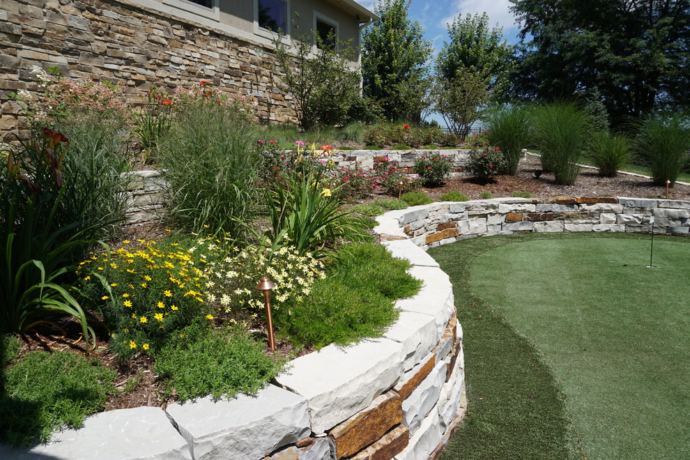 Large classic back full sun garden in Other with a retaining wall and natural stone paving.