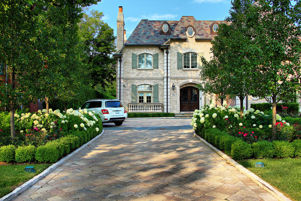 Пример оригинального дизайна: участок и сад на переднем дворе в классическом стиле с подъездной дорогой, мощением тротуарной плиткой и клумбами