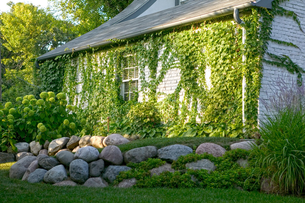 Idéer för vintage trädgårdar längs med huset, med en stödmur och naturstensplattor