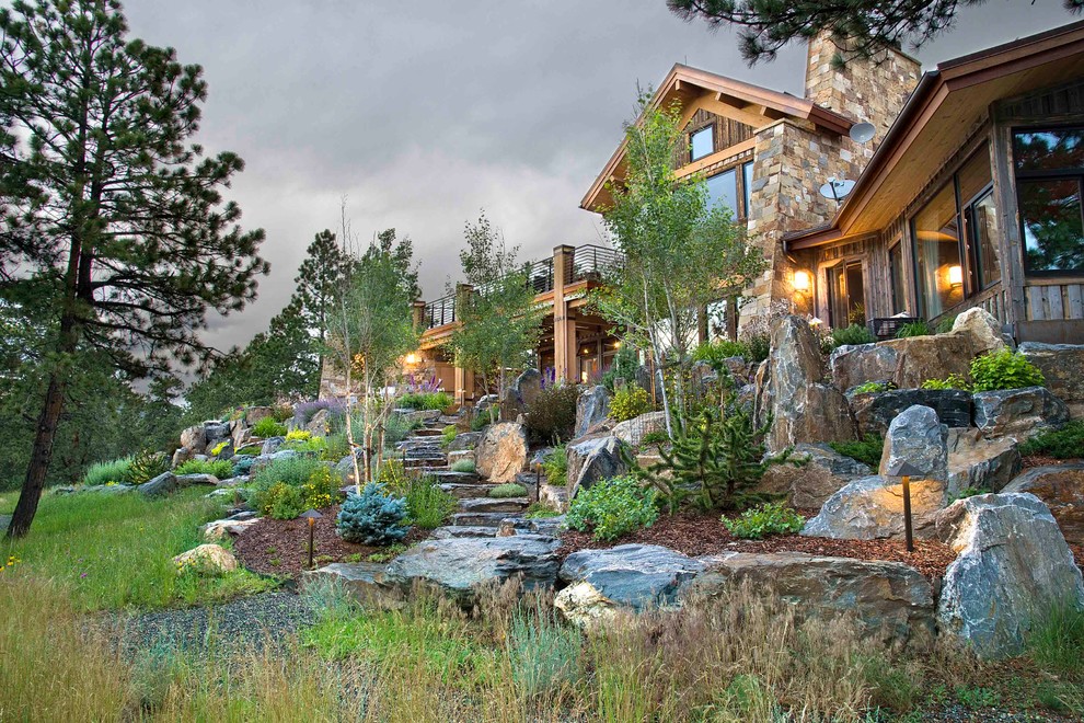 This is an example of an expansive eclectic sloped xeriscape garden in Denver with natural stone paving.