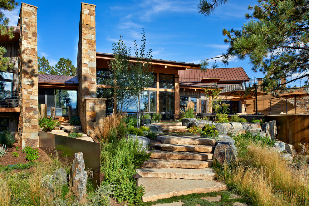 Photo of an expansive bohemian sloped xeriscape garden in Denver with a fire feature and natural stone paving.