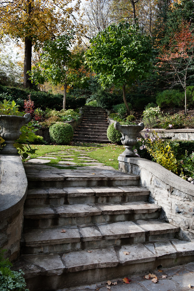 Ejemplo de jardín clásico en ladera con adoquines de piedra natural