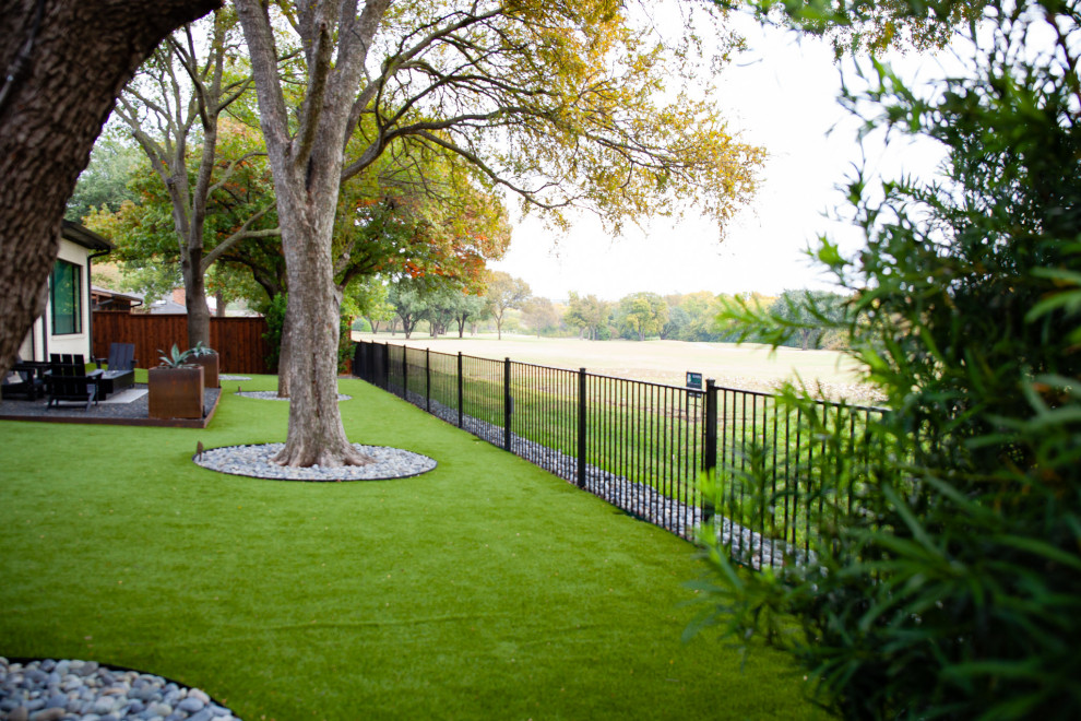 Inspiration for a mid-sized modern rock and shade backyard river rock and wood fence landscaping in Dallas.