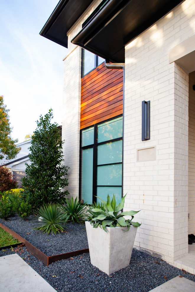Imagen de acceso privado moderno de tamaño medio en patio delantero con roca decorativa, exposición total al sol, gravilla y con madera