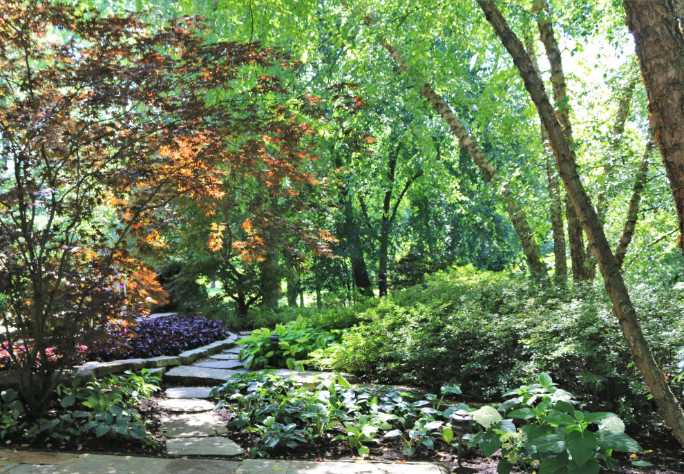 Réalisation d'un grand aménagement d'entrée ou allée de jardin avant tradition l'été avec une exposition partiellement ombragée et des pavés en pierre naturelle.