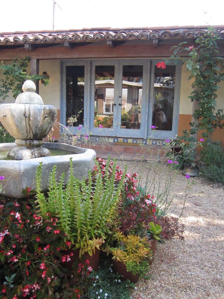 Modelo de jardín mediterráneo de tamaño medio en patio trasero con fuente y gravilla