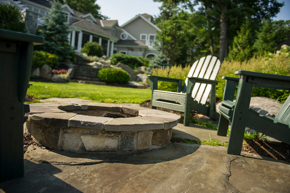 This is an example of a large traditional full sun backyard stone landscaping in Boston with a fire pit for summer.