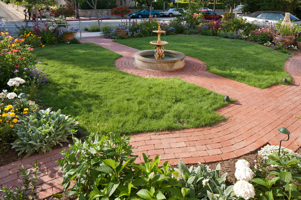 На фото: солнечный садовый фонтан среднего размера на переднем дворе в классическом стиле с хорошей освещенностью и мощением клинкерной брусчаткой
