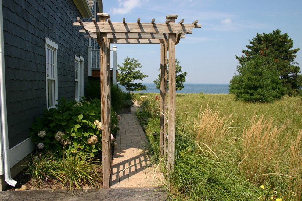 На фото: огромный участок и сад на боковом дворе в морском стиле с мощением клинкерной брусчаткой и с перголой с