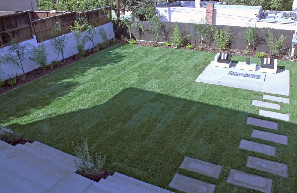 Geräumiger Moderner Garten hinter dem Haus mit Feuerstelle, direkter Sonneneinstrahlung und Betonboden in Los Angeles
