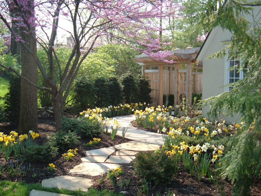 Modelo de jardín tradicional de tamaño medio en primavera en patio trasero con adoquines de piedra natural y exposición parcial al sol