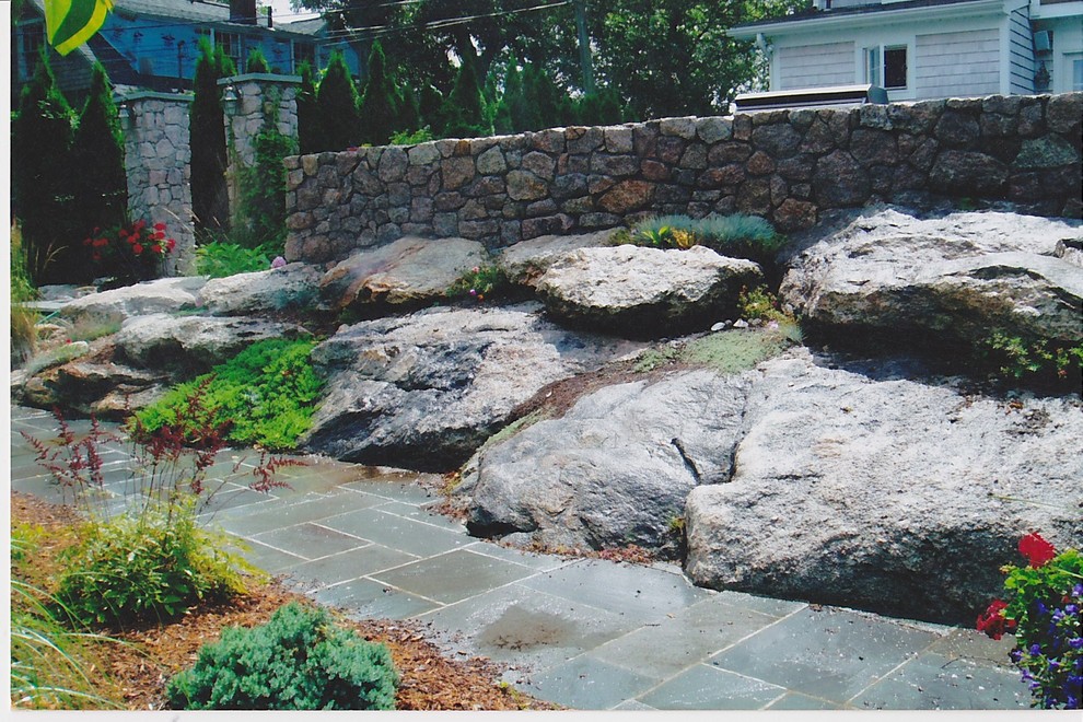 Immagine di un giardino tradizionale davanti casa con un muro di contenimento e pavimentazioni in pietra naturale