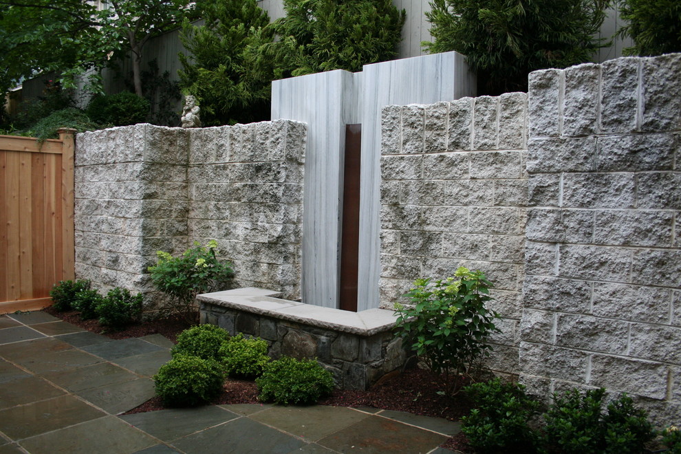 This is an example of a large modern partial sun backyard stone water fountain landscape in DC Metro.