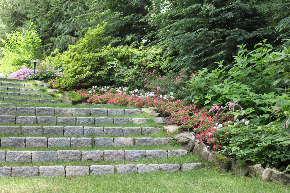 Aménagement d'un grand jardin arrière classique avec une exposition ombragée et des pavés en pierre naturelle.